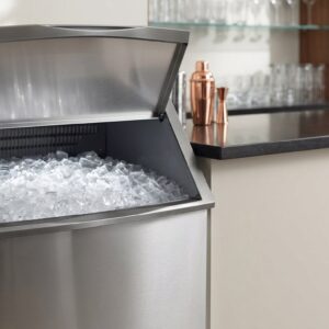 Freshly cleaned commercial ice machine full of clear cube ice beside a bar